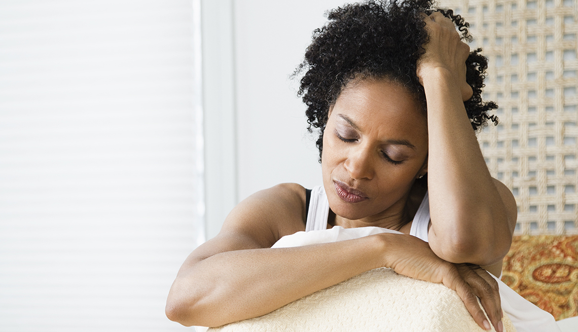 Mid adult woman sitting on the bed and suffering from a headache